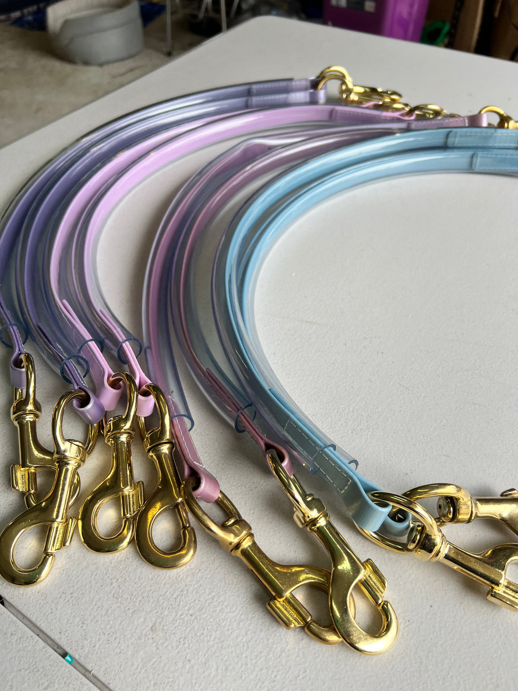 Assorted colour Biothane race day tie-ups with brass clips and clear tubing cover flat lay — SS Saddlery