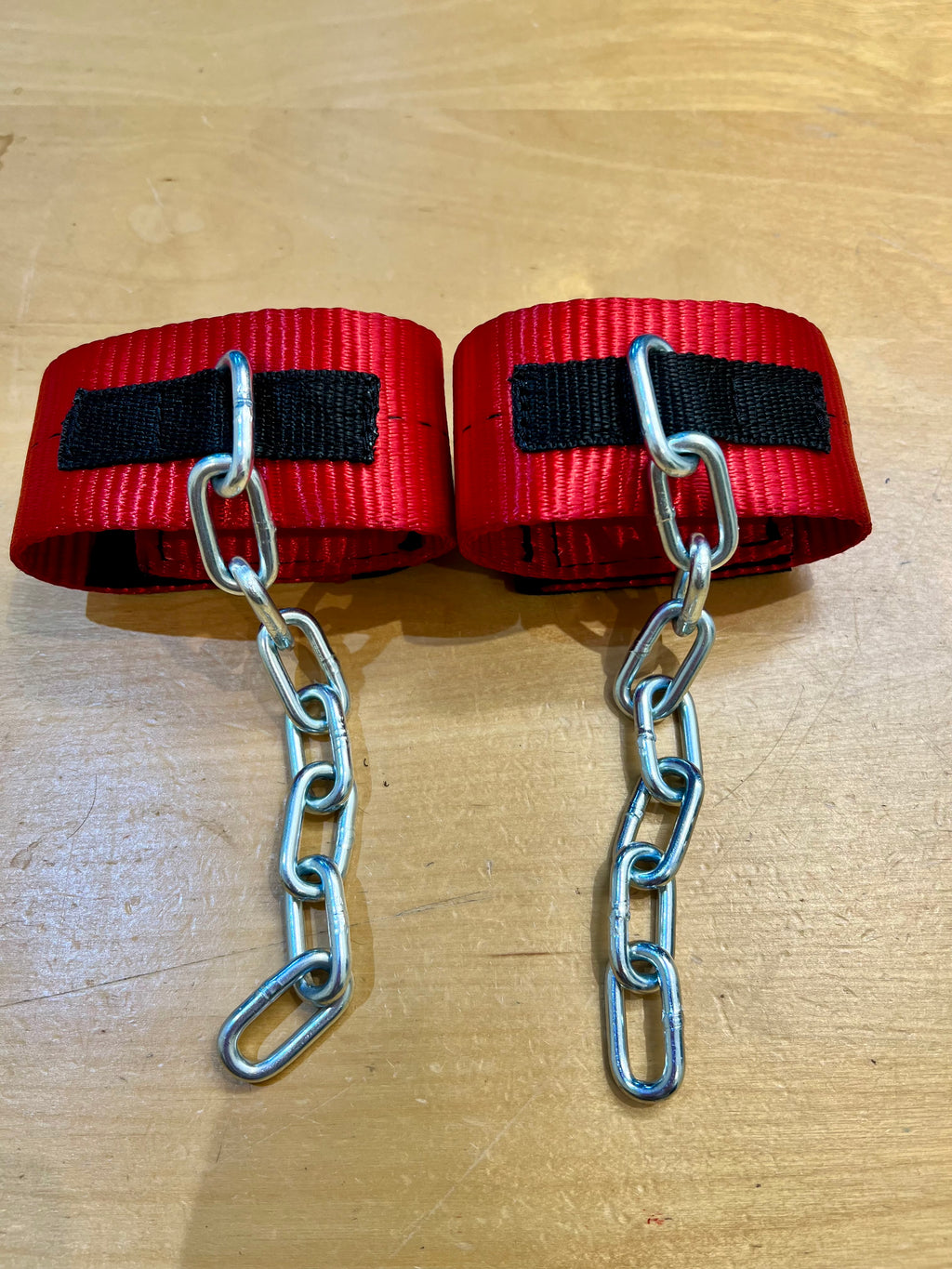 Red anti pawing cuffs with chains flat lay on wooden surface — SS Saddlery