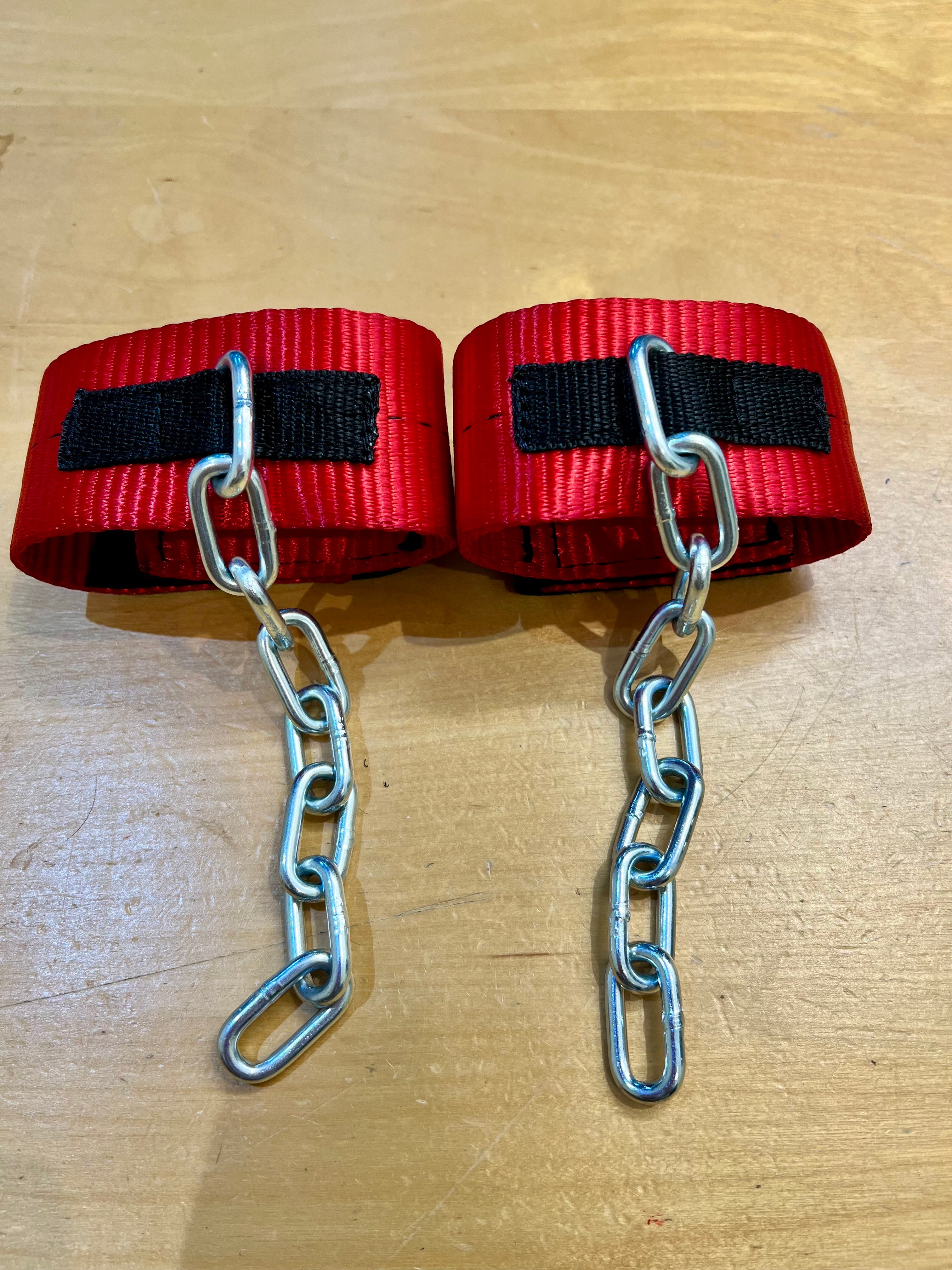 Red anti pawing cuffs with chains flat lay on wooden surface — SS Saddlery